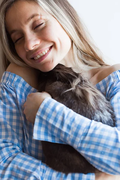 Mascotas y concepto de Pascua - Muchacha atractiva abrazando conejo marrón en casa, primer plano . — Foto de Stock