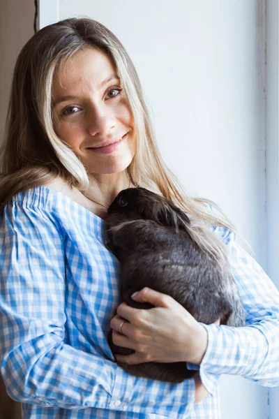 Концепция домашних животных и Пасхи - девочка обнимает дома коричневого кролика . — стоковое фото