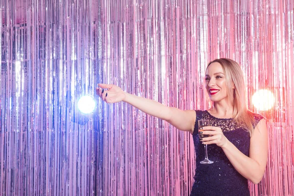 Party, drinks, holidays and celebration concept - smiling woman in evening dress with glass of sparkling wine over shiny background.