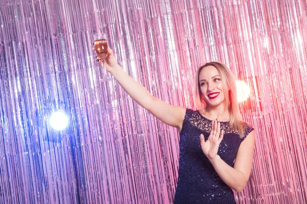 Party, drinks, holidays and celebration concept - smiling woman in evening dress with glass of sparkling wine over shiny background.