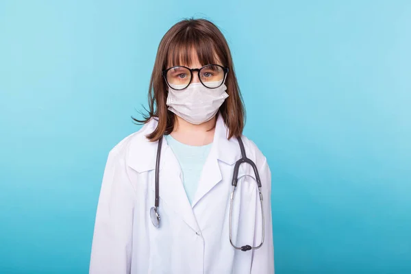 Concept de virus, pandémie, quarantaine et épidémie - enfant habillé en médecin debout sur fond bleu . — Photo