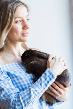 Evcil hayvan ve Paskalya konsepti - Mutlu kız evde kahverengi tavşana sarılıyor.