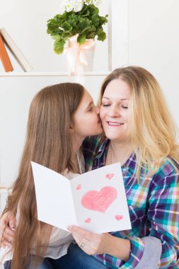 Anneler Günü ve aile tatilleri - Anne kızından tebrik kartı okuyor.