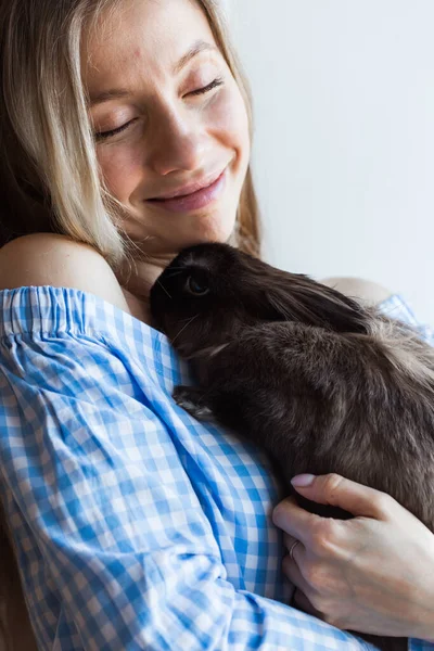 Концепция домашних животных и Пасхи - Счастливая девочка обнимает дома коричневого кролика . — стоковое фото