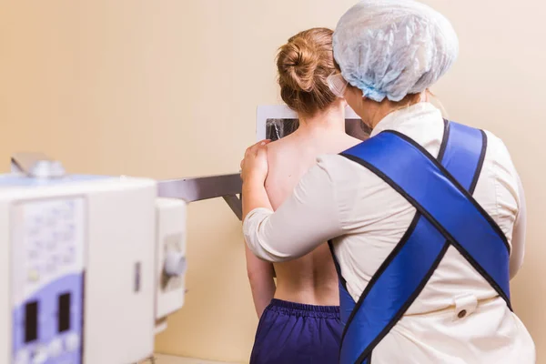 診察室で胸部X線の患者を準備する女性看護師. — ストック写真