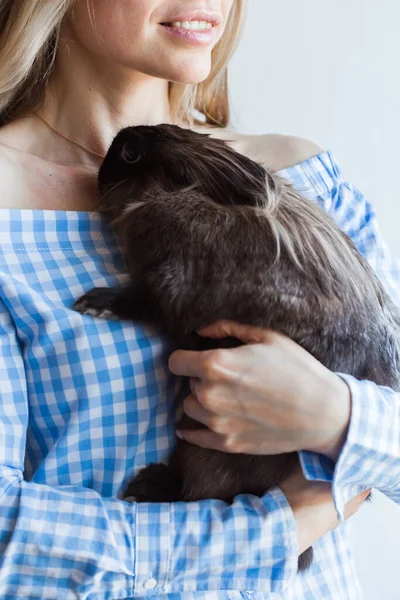 Концепция домашних животных и Пасхи - Счастливая девочка обнимает дома коричневого кролика . — стоковое фото