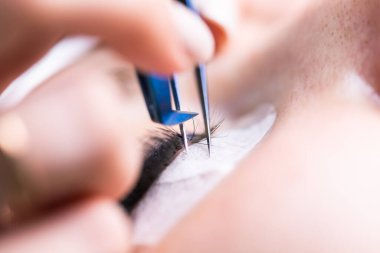 Kirpik uzatma prosedürü. Uzun kirpikli kadın gözü. Kırbaçlar, kapatın, makro, seçici odaklanma.