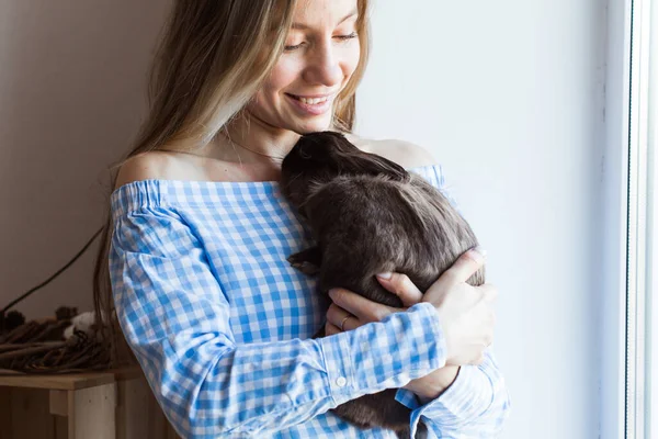 Mascotas y concepto de Pascua - Chica feliz abrazando conejo marrón en casa . — Foto de Stock