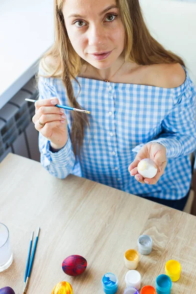 Holidays, handmade and creation concept - Happy young woman draws on Easter egg. — Stock Photo, Image