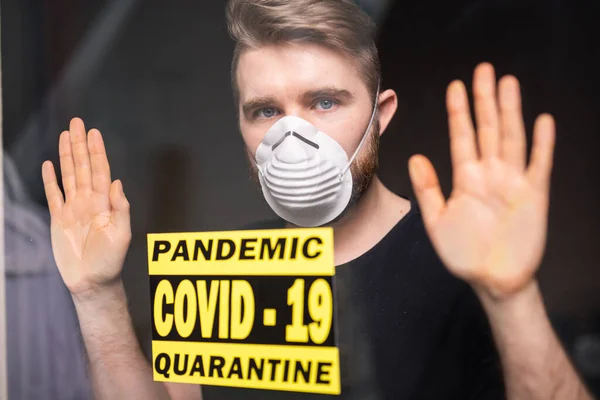 Coronavirus, quarantaine, covid-19 en pandemie concept. Droevige en zieke man van het corona virus die door het raam kijkt. Blijf thuis.. — Stockfoto