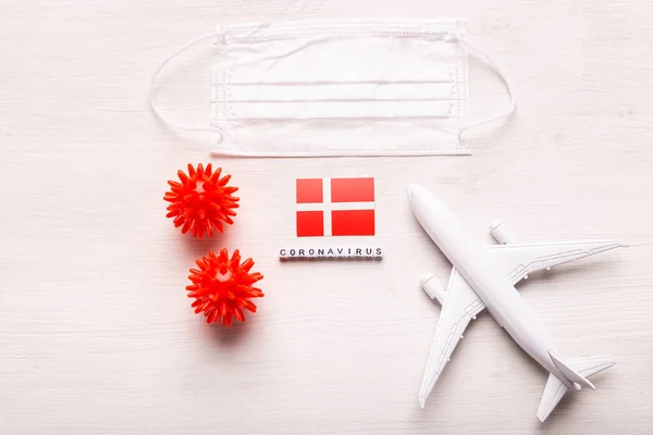 Modelo de avión y máscara facial y bandera de Dinamarca. pandemia de Coronavirus. Prohibición de vuelos y fronteras cerradas para turistas y viajeros con coronavirus covid-19 de Europa y Asia . — Foto de Stock