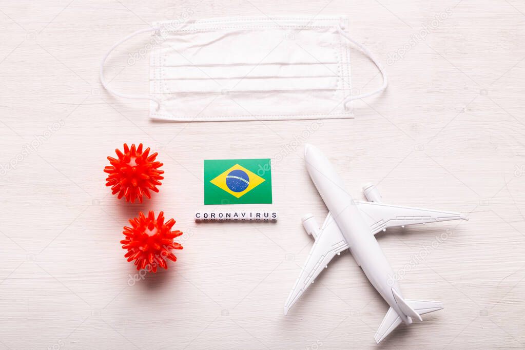 Plane model and face mask and flag Brazil. Coronavirus pandemic. Flight ban and closed borders for tourists and travelers with coronavirus covid-19 from Europe and Asia.