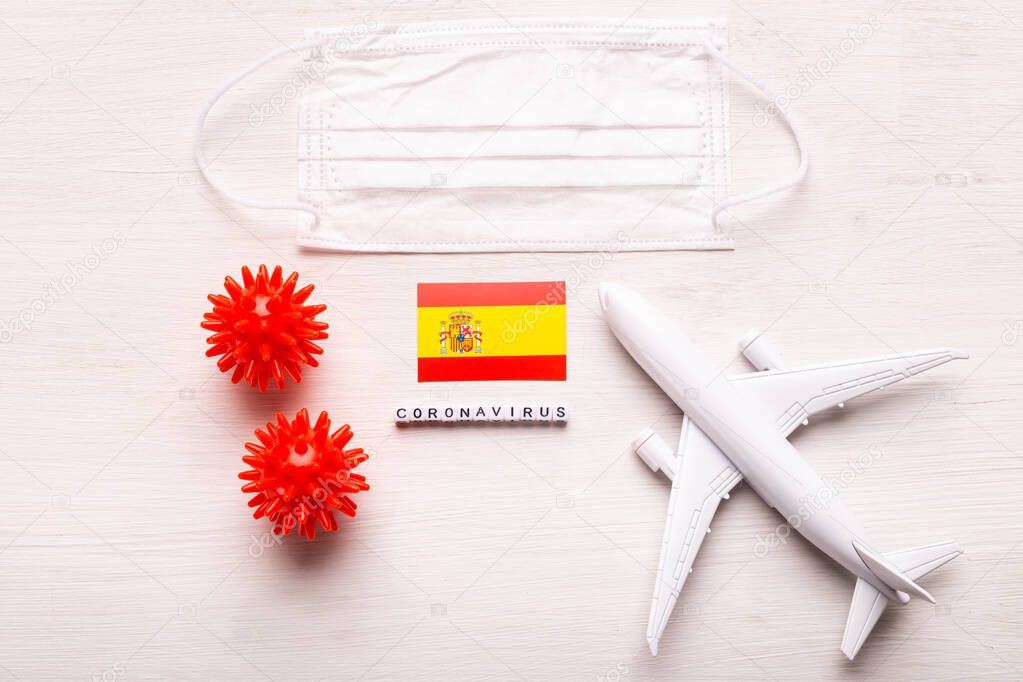 Plane model and face mask and flag Spain. Coronavirus pandemic. Flight ban and closed borders for tourists and travelers with coronavirus covid-19 from Europe and Asia.
