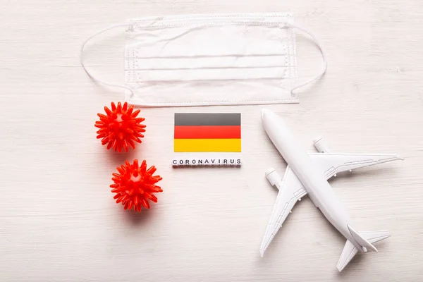 Modelo de avión y máscara facial y bandera de Alemania. pandemia de Coronavirus. Prohibición de vuelos y fronteras cerradas para turistas y viajeros con coronavirus covid-19 de Europa y Asia . — Foto de Stock