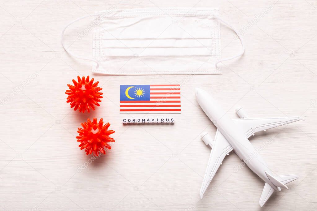 Plane model and face mask and flag Malaysia. Coronavirus pandemic. Flight ban and closed borders for tourists and travelers with coronavirus covid-19 from Europe and Asia.