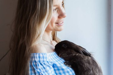 Evcil hayvan ve Paskalya konsepti - Mutlu kız evde kahverengi tavşana sarılıyor.