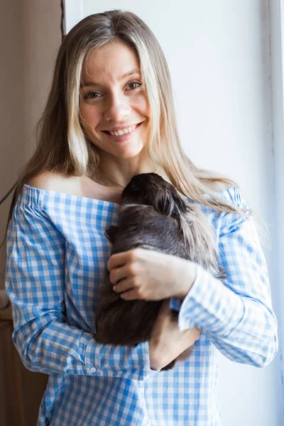 Pet e conceito de Páscoa - Menina feliz abraçando coelho marrom em casa . — Fotografia de Stock