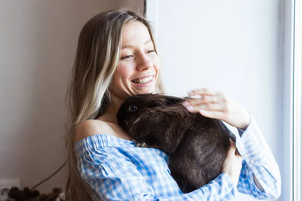 Mascotas y concepto de Pascua - Chica feliz abrazando conejo marrón en casa . — Foto de Stock