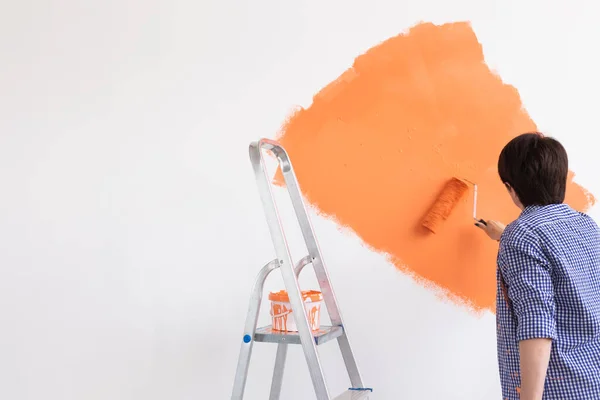 Concetto di ristrutturazione, ridecorazione e riparazione - parete di pittura donna di mezza età in una nuova casa. — Foto Stock