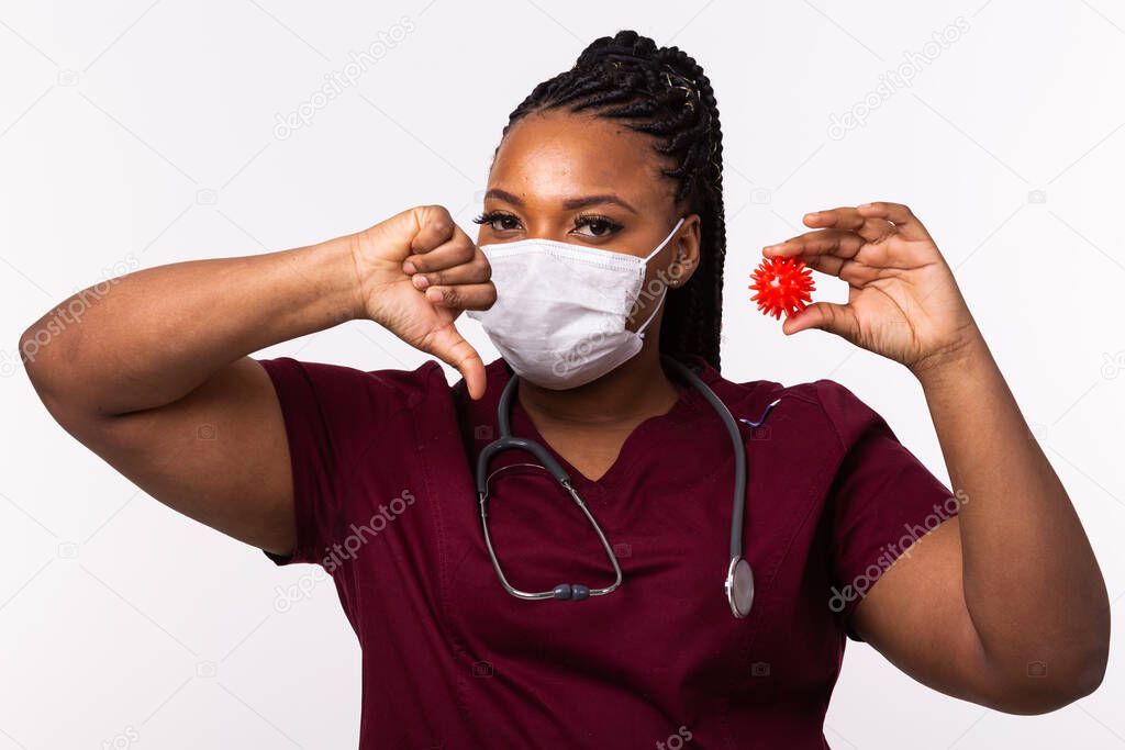 Covid-19, Vaccine development , outbreak and medicine concept - Doctor in medical protective mask holding a model of coronavirus and showing thumb down gesture on white background.