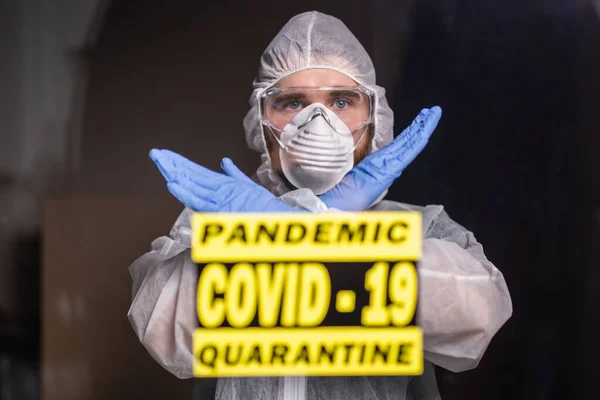 Man in protective suit and in protective medical mask showing stop gesture. Epidemiologist show gesture no. Stop coronavirus or covid-19 and the pandemic. Stay home. Quarantine concept.
