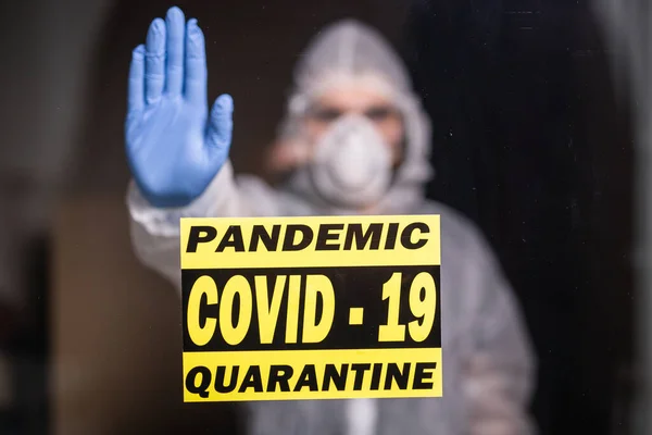 Man in protective suit and in protective medical mask showing stop gesture. Epidemiologist show stop palm. Stop coronavirus or covid-19 and the pandemic. Stay home. Quarantine concept.