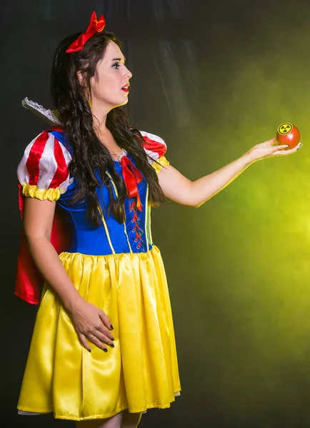 Kobieta ubrana jak postać z bajki posiada radioaktywny atomowy symbol ostrzegawczy przed promieniowaniem jonizującym na jabłku. Koncepcja pomiaru energii jądrowej i promieniowania. — Zdjęcie stockowe