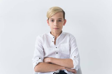 Yalnızlık, yalnızlık ve can sıkıntısı konsepti - Beyaz arka planda izole bir okul koltuğunda oturan sıkıcı genç öğrenci