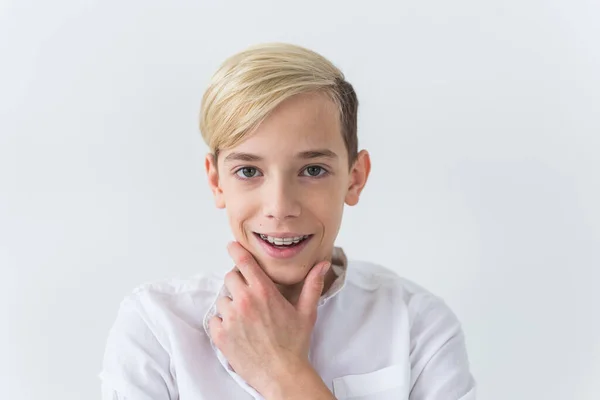 Närbild av tonåring pojke med hängslen på tänderna ler på vit bakgrund. Tandvård och tonårsidé. — Stockfoto