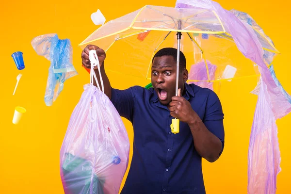Πρόβλημα των απορριμμάτων, ανακύκλωση πλαστικών, ρύπανση και περιβαλλοντική αντίληψη-έκπληκτος άνθρωπος που μεταφέρουν σακούλα σκουπιδιών σε κίτρινο φόντο — Φωτογραφία Αρχείου