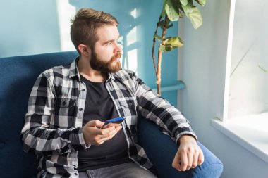Teknoloji ve eğlence konsepti. Evde akıllı telefon kullanan yakışıklı bir adam..