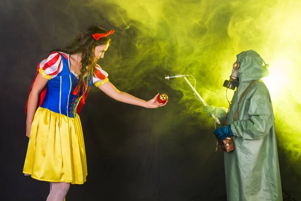 Eine als Märchenfigur verkleidete Frau hält ein Warnsymbol für radioaktive atomare ionisierende Strahlung auf einem Apfel. Kern- und Strahlenmesskonzept. — Stockfoto