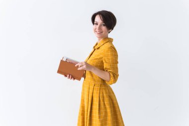 Beyaz arka plan üzerine kitap okuyan sarı retro elbiseli güzel esmer bir kızın portresi. kopyalama alanı ile.