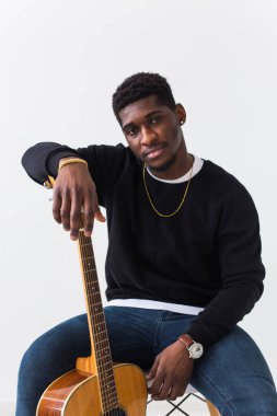 Gitarlı, afro saçlı, yakışıklı Afro-Amerikalı bir adam. Beyaz arkaplanda fotokopi alanı olan bir portre. Kameraya bakan adam..