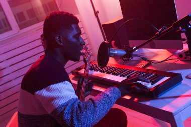 Afro-Amerikan profesyonel müzisyen kayıt sentezleyicisi dijital stüdyoda, müzik üretim teknolojisi konsepti, yakın çekim.