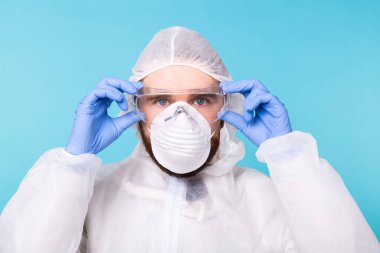 Biyolojik tehlike kıyafeti giyen doktor ya da labaratuar bilim adamı güvenlik gözlüğü takar, yüzünü kapatır. Coronavirus, covid-19 ve pandemik konsept.