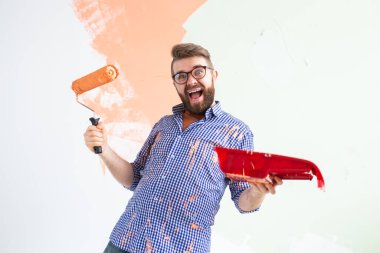 Yeni evin duvarlarını boyayan komik adam. Yenileme, onarım ve yeniden dekorasyon konsepti.