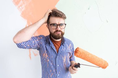 Evin içini boyayan kafası karışmış komik bir adam. Yenileme, onarım ve yeniden dekorasyon konsepti.