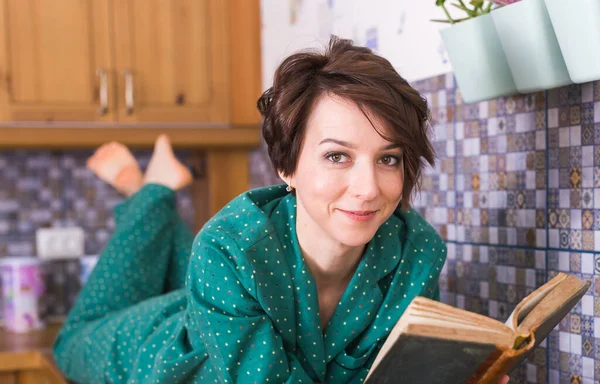 Mulher feliz usa pijama e relaxante em casa e ler um livro. Fica em casa. Conceito de coronavírus pandémico de quarentena . — Fotografia de Stock