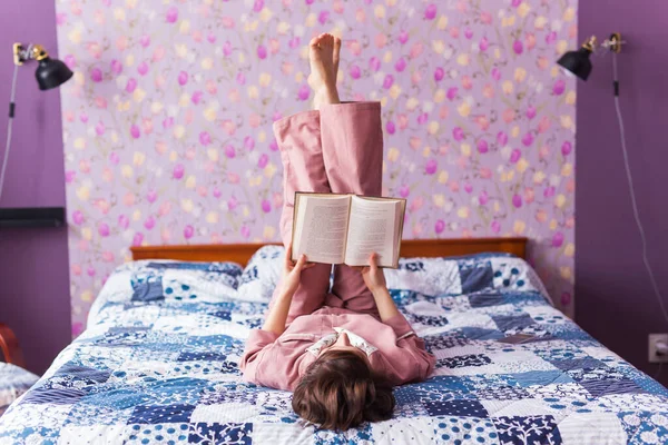 Mujer feliz lleva pijama y relajarse en casa y leer un libro. Quédate en casa. Concepto de coronavirus pandémico de cuarentena . — Foto de Stock