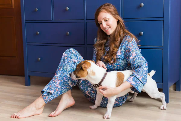 Joyeux jeune femme assise avec son chien à la maison. Propriétaire d'animal, animaux et concept d'amitié . — Photo