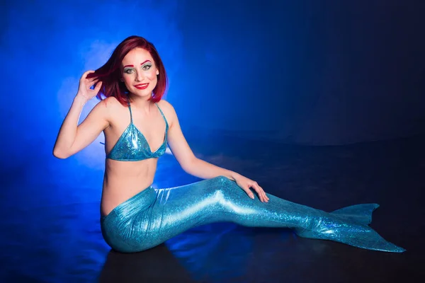 Red hair beautiful siren mermaid underwater in the deep blue sea. Mythology and legend concept.
