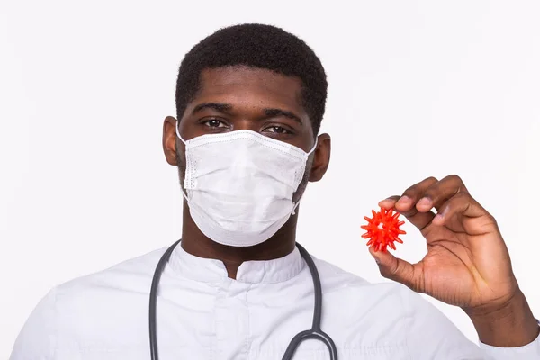 Docteur en gants stériles tenant une maquette du virus du nouveau coronavirus COVID-19 comme cas dangereux de souche grippale comme une pandémie. Concept d'épidémie mondiale. Fond blanc, gros plan . — Photo