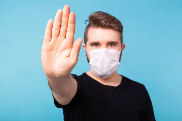 Un bel homme qui montre un arrêt de geste. Photo de l'homme en bonne santé porte un masque de protection contre les maladies infectieuses et la grippe. Soins de santé, concept covid-19 et coronavirus . — Photo
