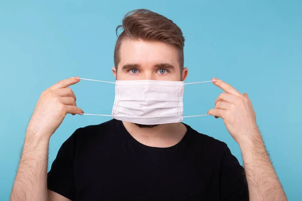 L'homme porte un masque protecteur jetable d'hygiène médicale blanche pour se protéger des maladies respiratoires, virales infectieuses, du coronavirus covid-19. Protection contre le coronavirus, contagieux — Photo