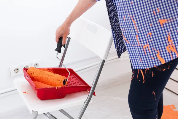 Sluit een vrouw van middelbare leeftijd die muren schildert in haar nieuwe appartement. Renovatie, herinrichting en reparatie concept. — Stockfoto