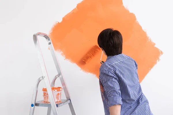 Mulher de meia-idade pintando as paredes da nova casa. Conceito de renovação, reparação e redecoração. — Fotografia de Stock