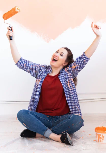 Reparación en el apartamento. Mujer feliz pinta la pared con pintura. — Foto de Stock