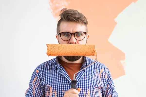 Reparación en el apartamento. El hombre gracioso pinta la pared con pintura . — Foto de Stock