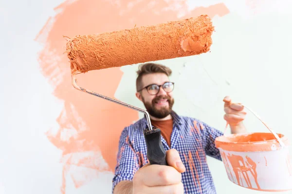 Funny man with painting roller indoors. Redecoration, renovation, apartment repair and refreshment concept. — Stock Photo, Image